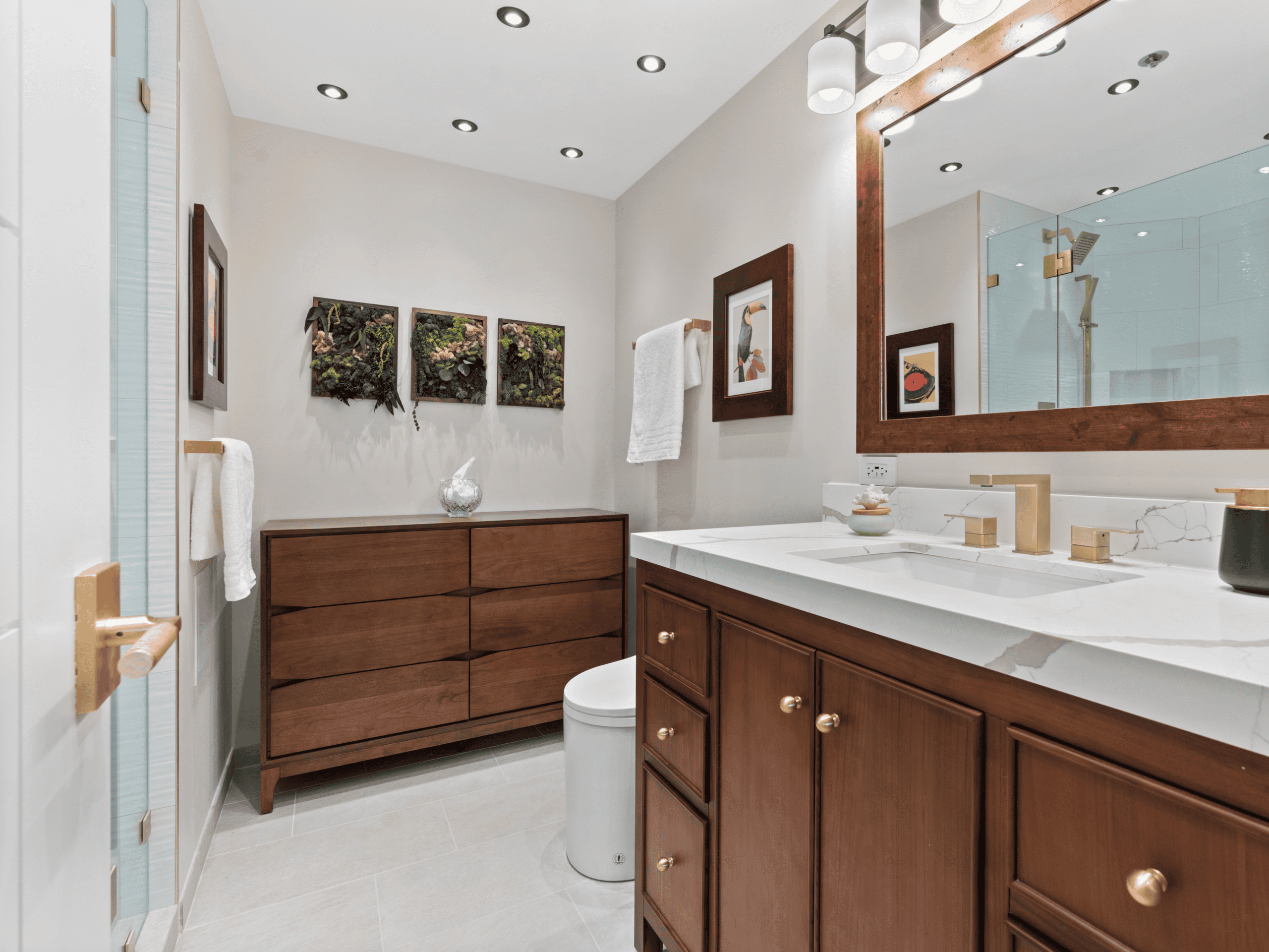 Elegant bathroom with wooden vanity, large mirror, and decorative wall art.