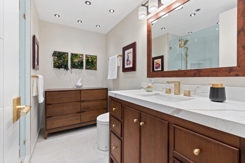 Elegant bathroom with wooden vanity, large mirror, and decorative wall art.