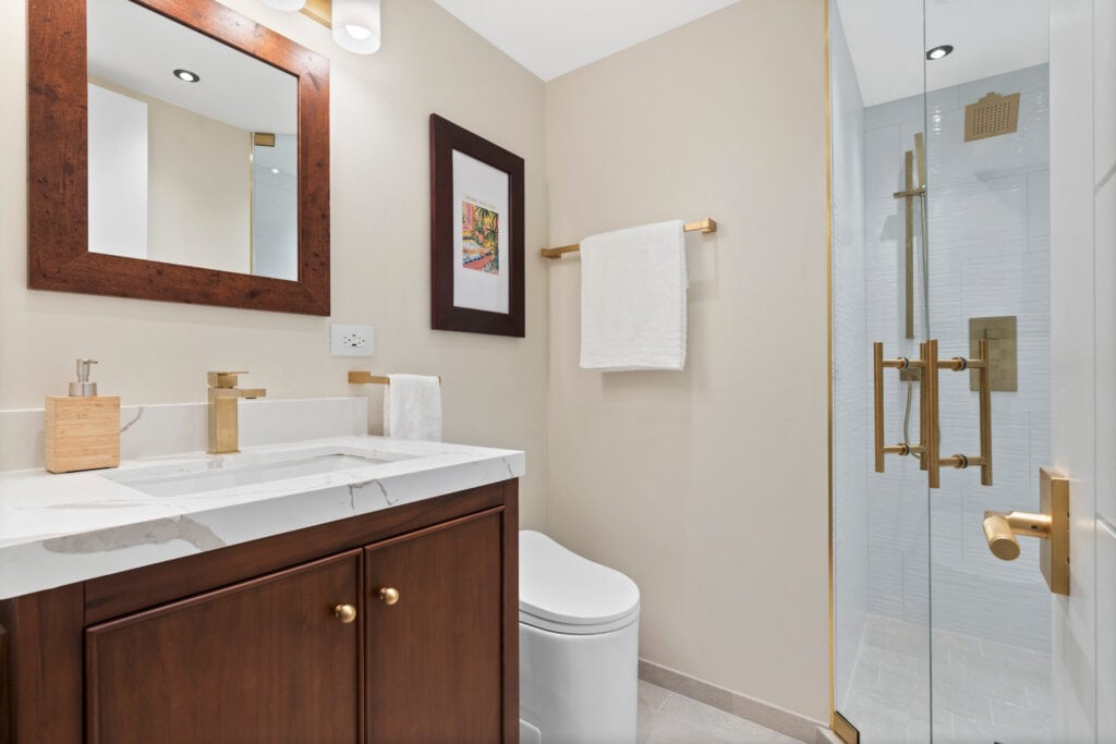 Contemporary bathroom with wooden vanity, glass shower, and neutral tones.