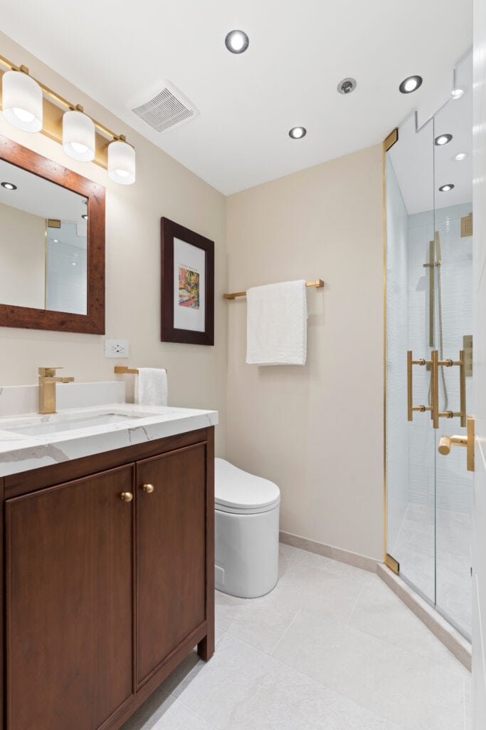 Contemporary bathroom with wooden vanity, glass shower, and modern lighting fixtures.