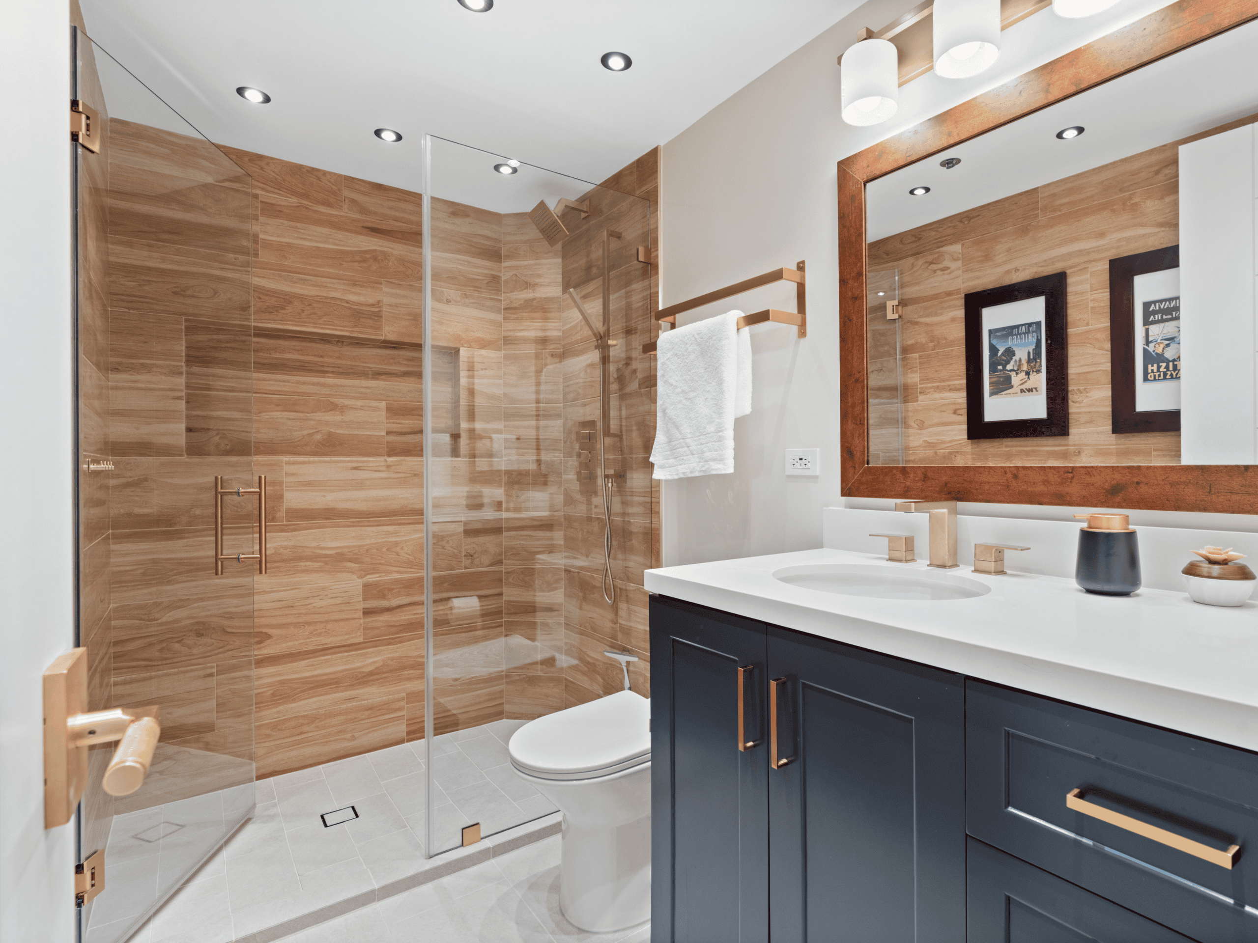 Contemporary bathroom with walk-in shower, navy vanity, and large mirror.