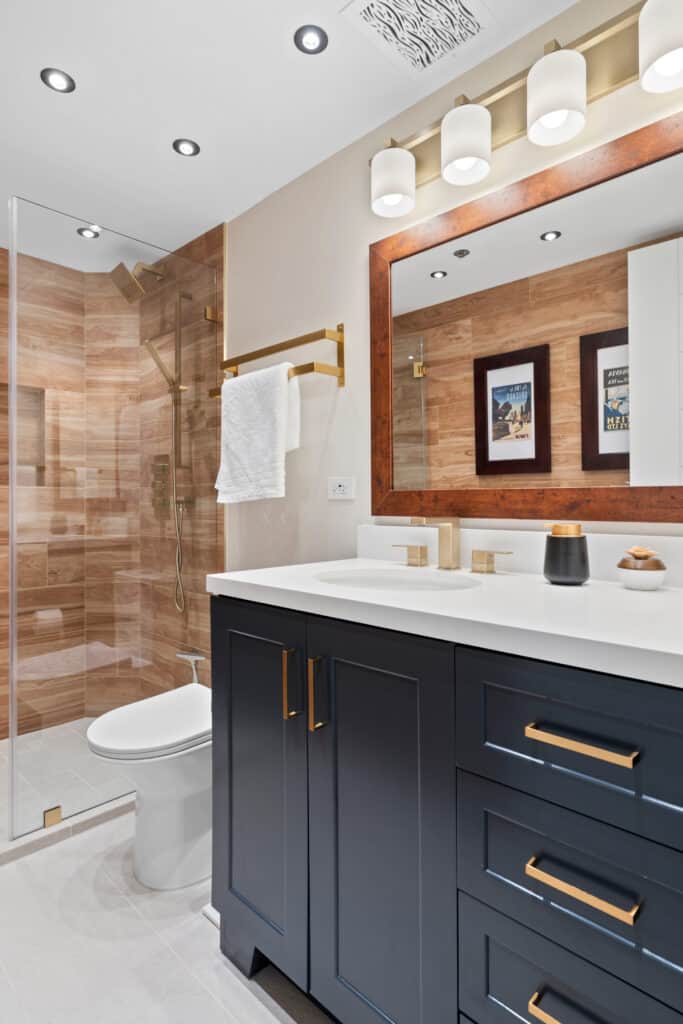 Contemporary bathroom with navy vanity, large mirror, and walk-in shower with glass enclosure.
