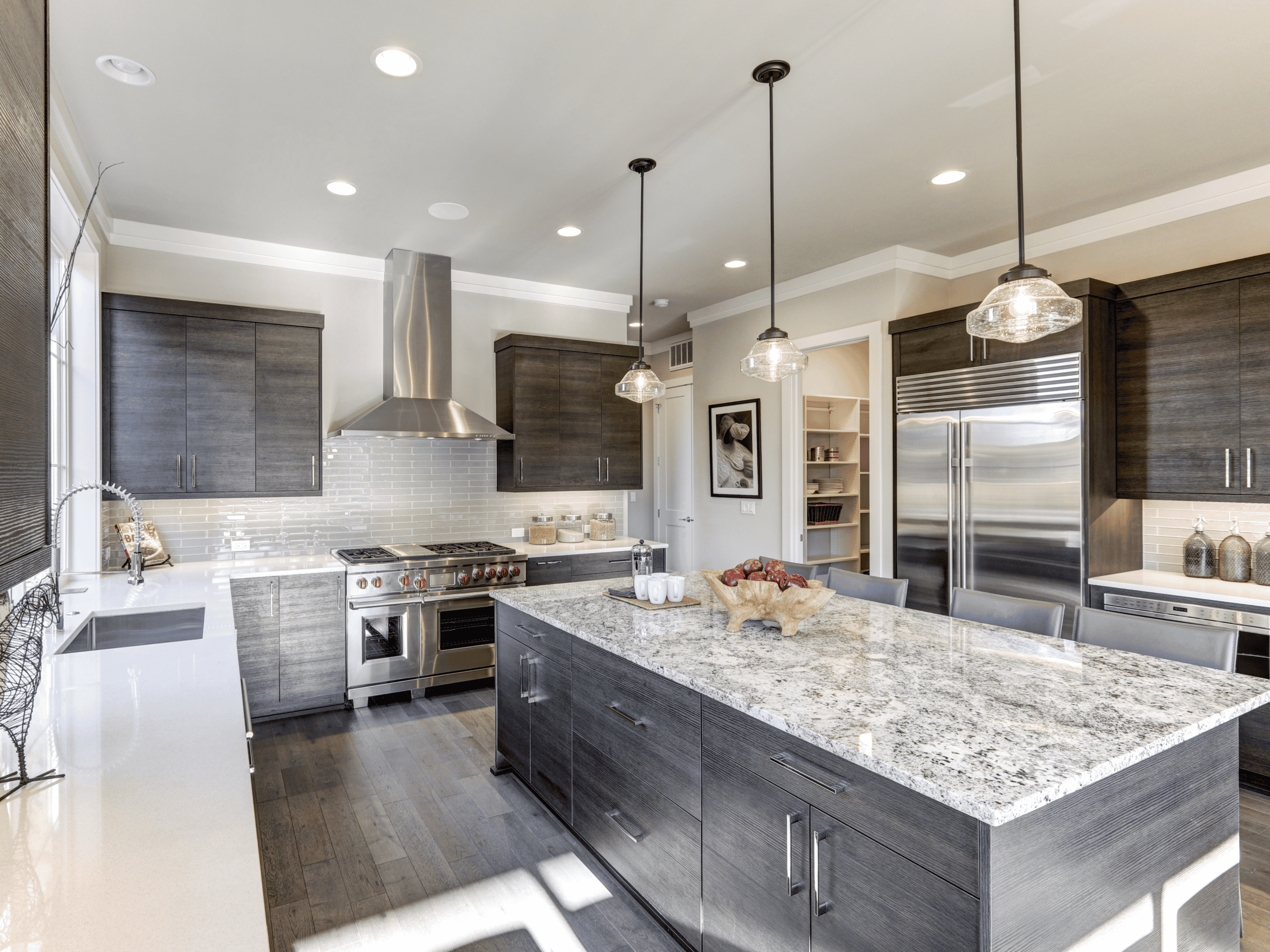 Contemporary kitchen with dark wood cabinets, granite island, and stainless steel appliances.