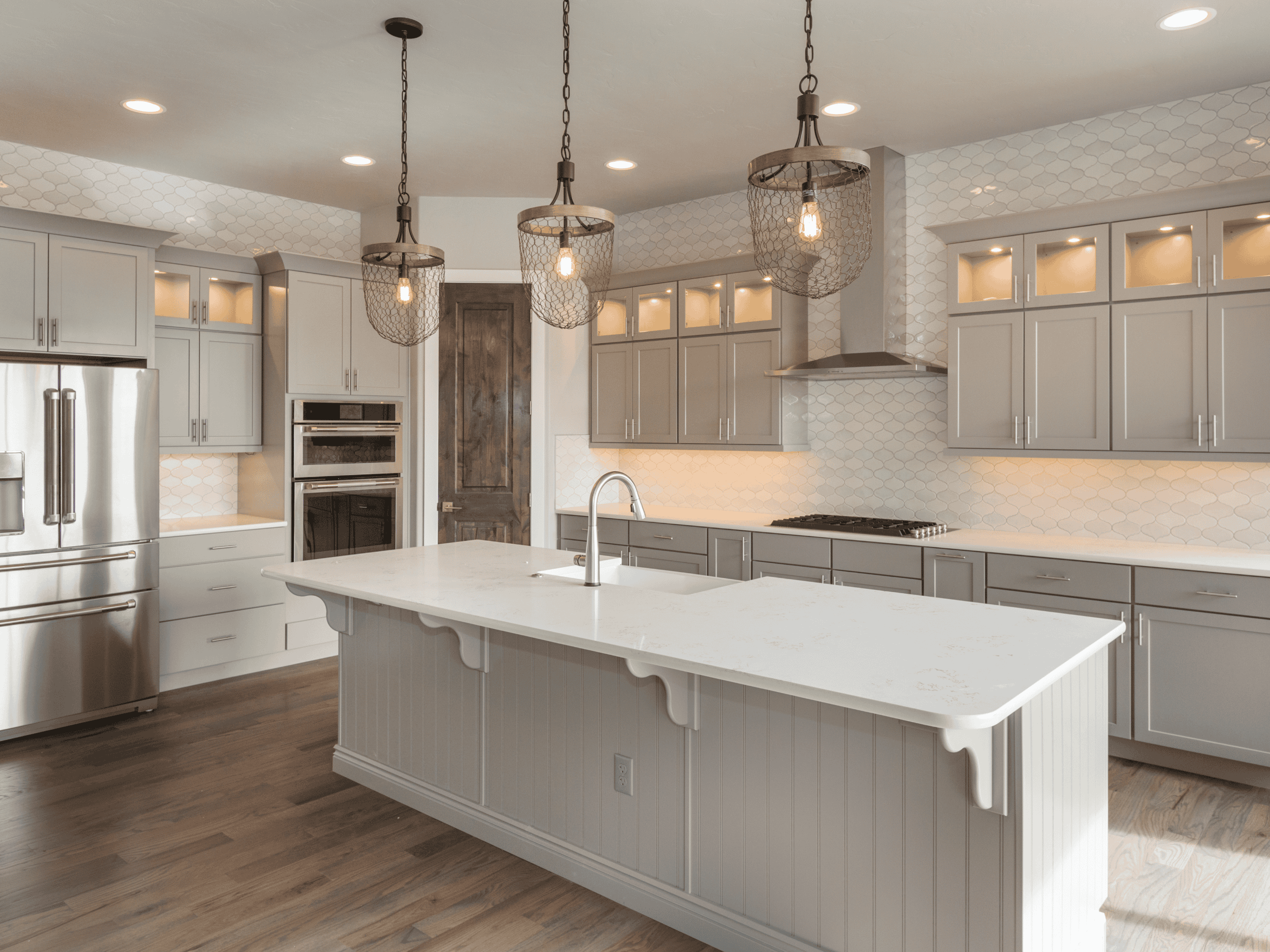Spacious modern kitchen with gray cabinets, island, and pendant lighting.