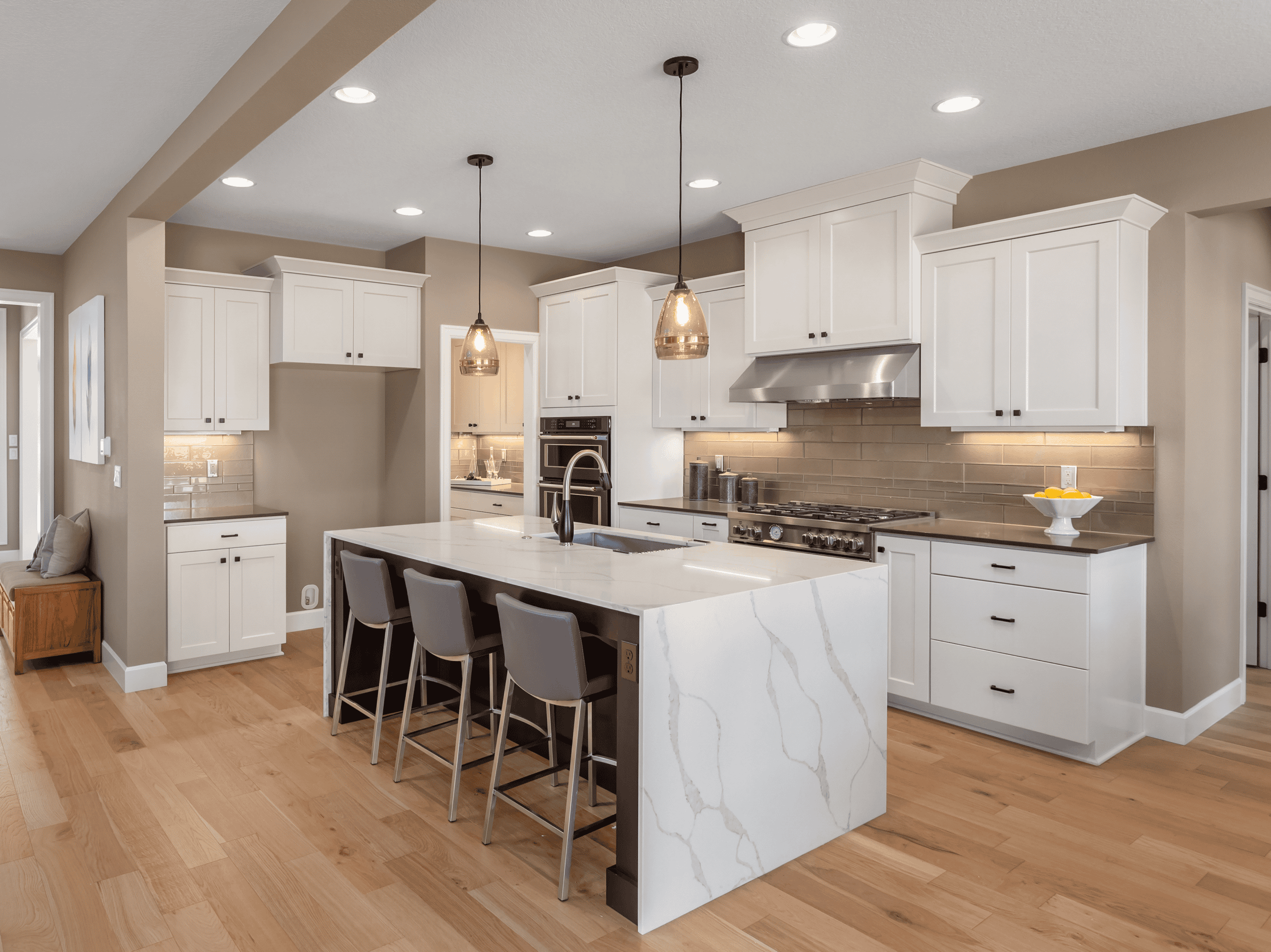 Spacious modern kitchen with white cabinets, marble island, and stainless steel appliances.