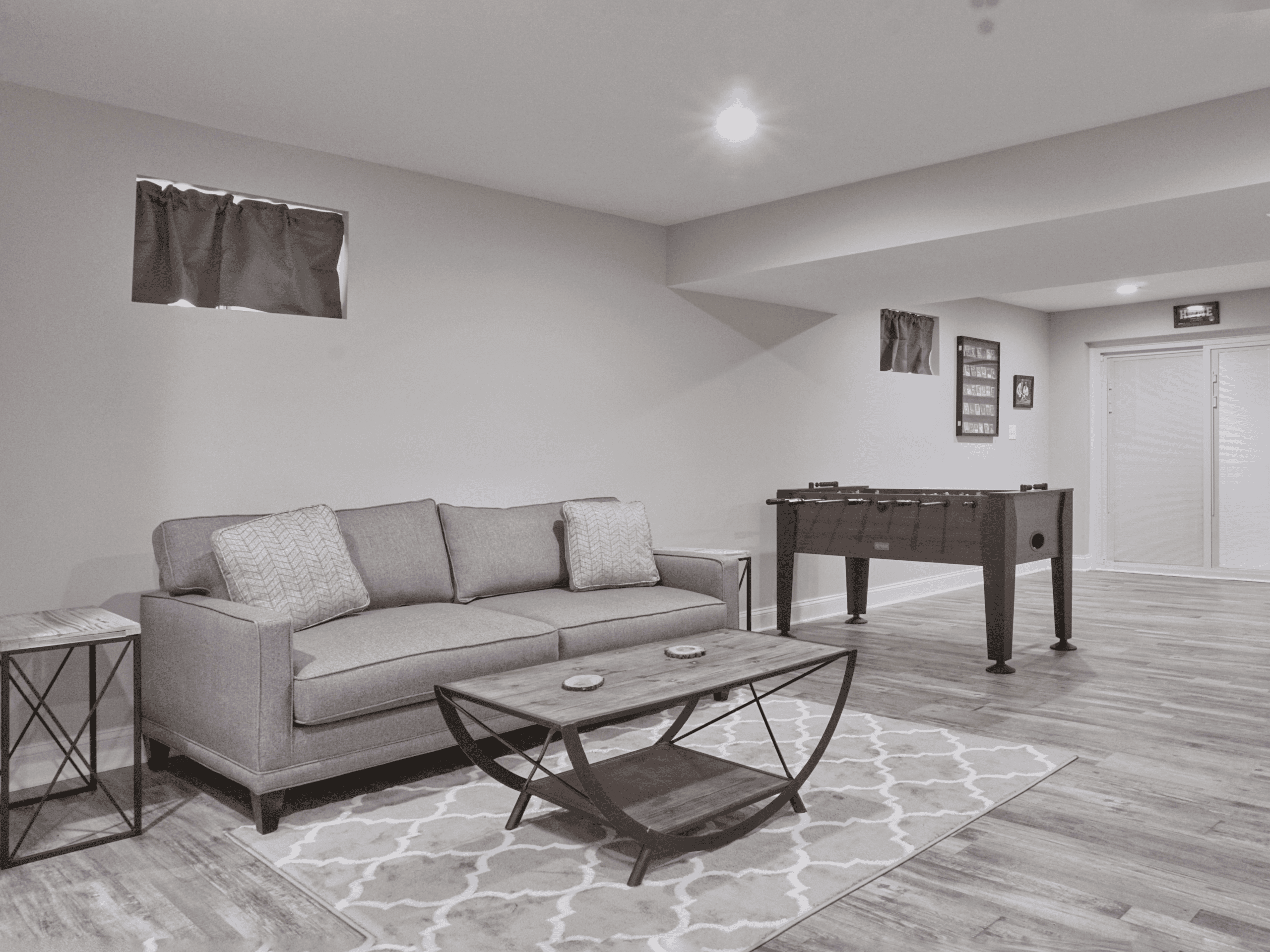 Example Co Basement Modern basement with gray sofa, foosball table, and contemporary decor.