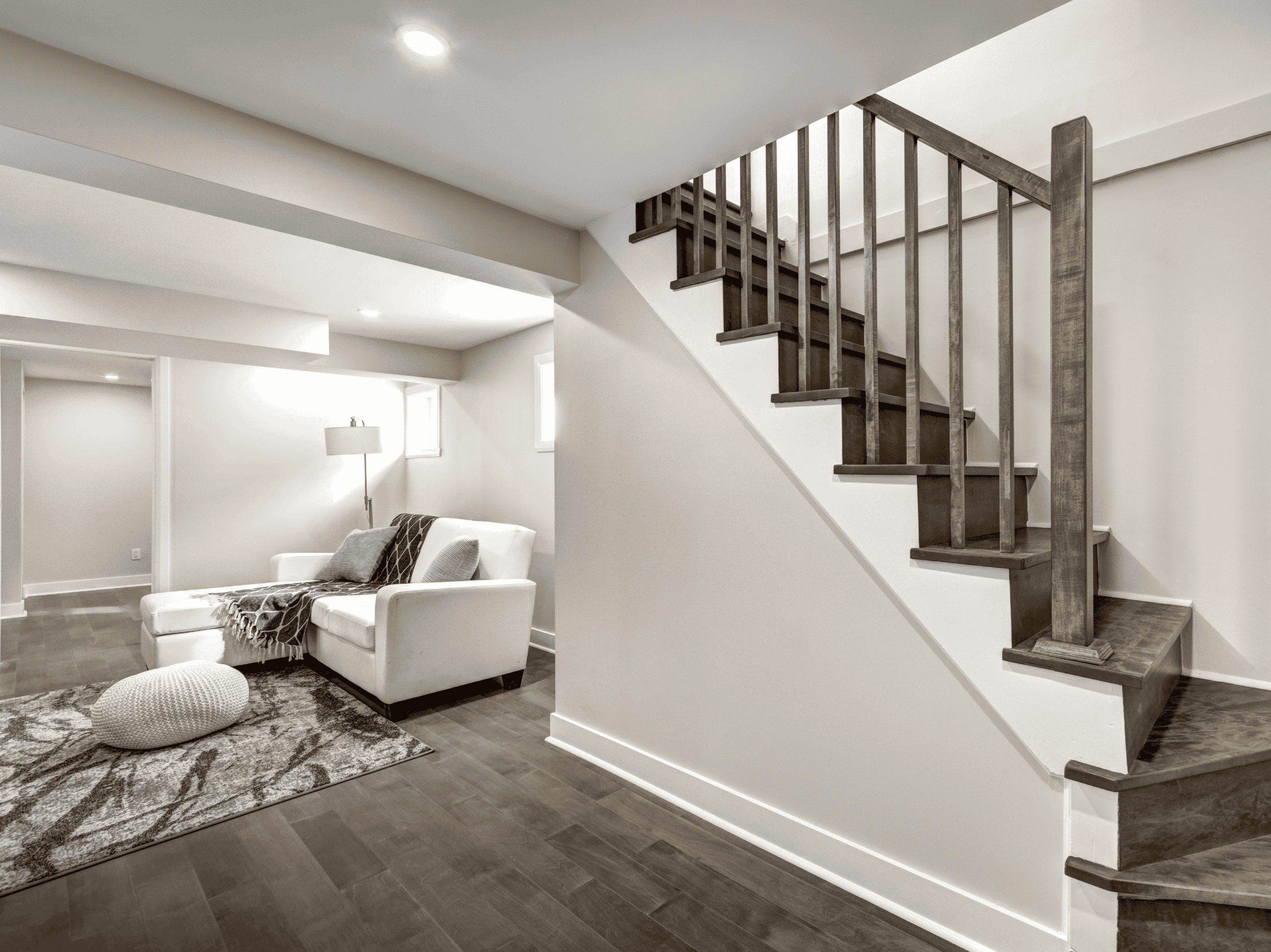 Modern Basement Living Bright modern basement with white sofa, wooden staircase, and cozy decor.