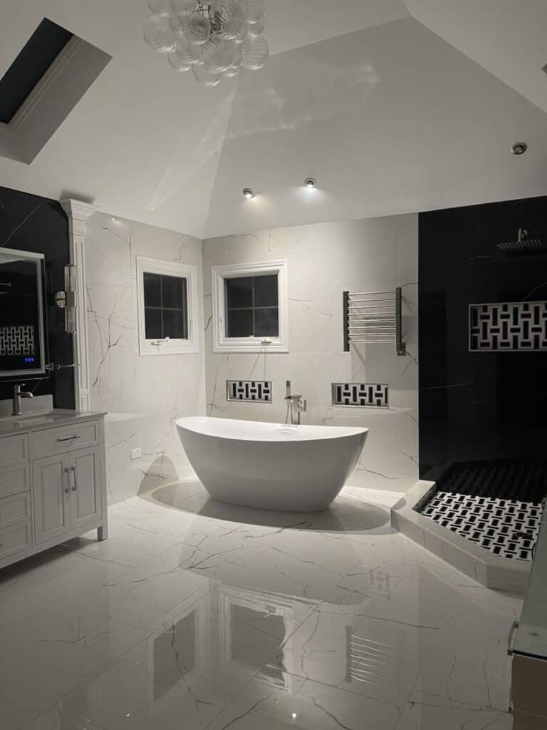 Modern bathroom with freestanding tub, black and white decor, and elegant fixtures.