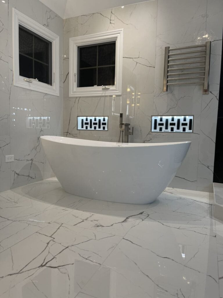 Modern bathroom with freestanding bathtub, marble walls, and stylish lighting fixtures.