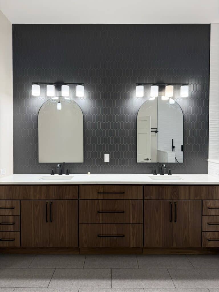 Double bathroom vanity with two mirrors and black hexagon tile wall.