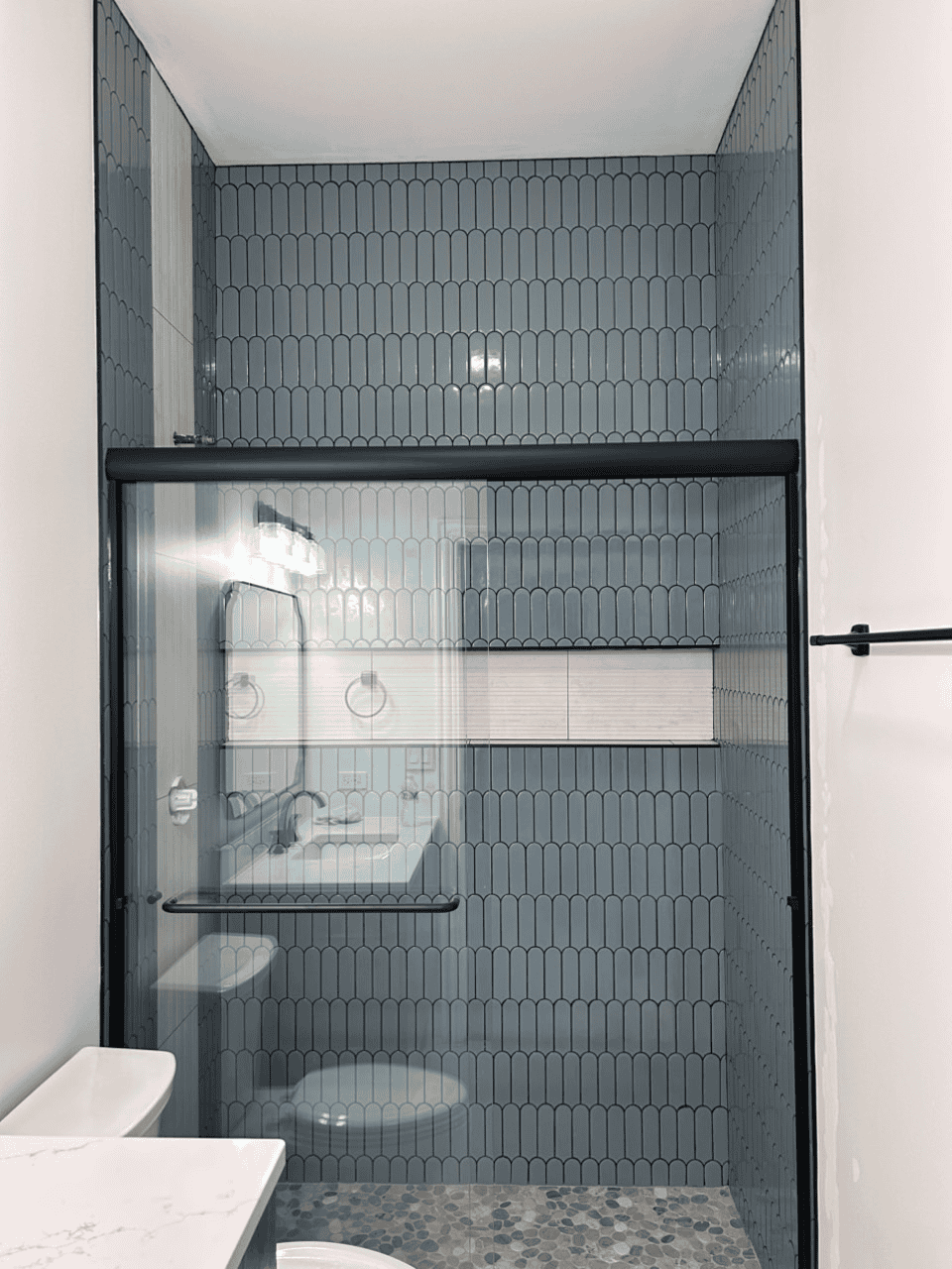 Contemporary bathroom with glass shower enclosure and blue tile walls.