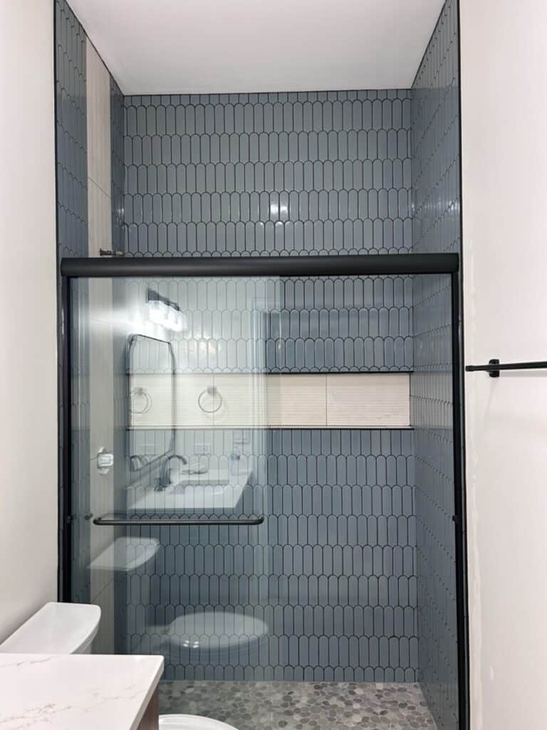 Contemporary bathroom with glass shower enclosure and blue tile walls.