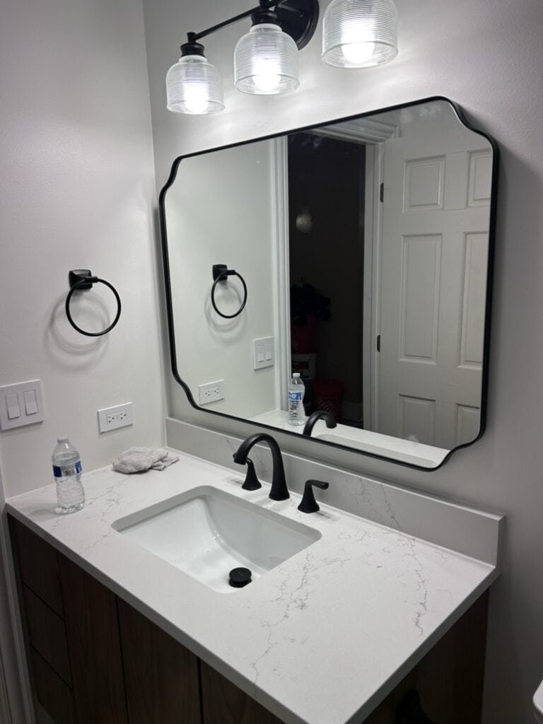 Contemporary bathroom with sleek vanity, large mirror, and stylish lighting fixtures.