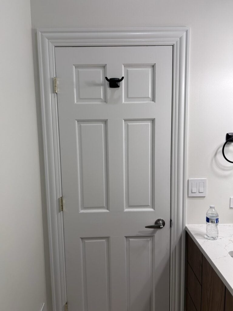 White interior door with black hook and silver handle in modern home.