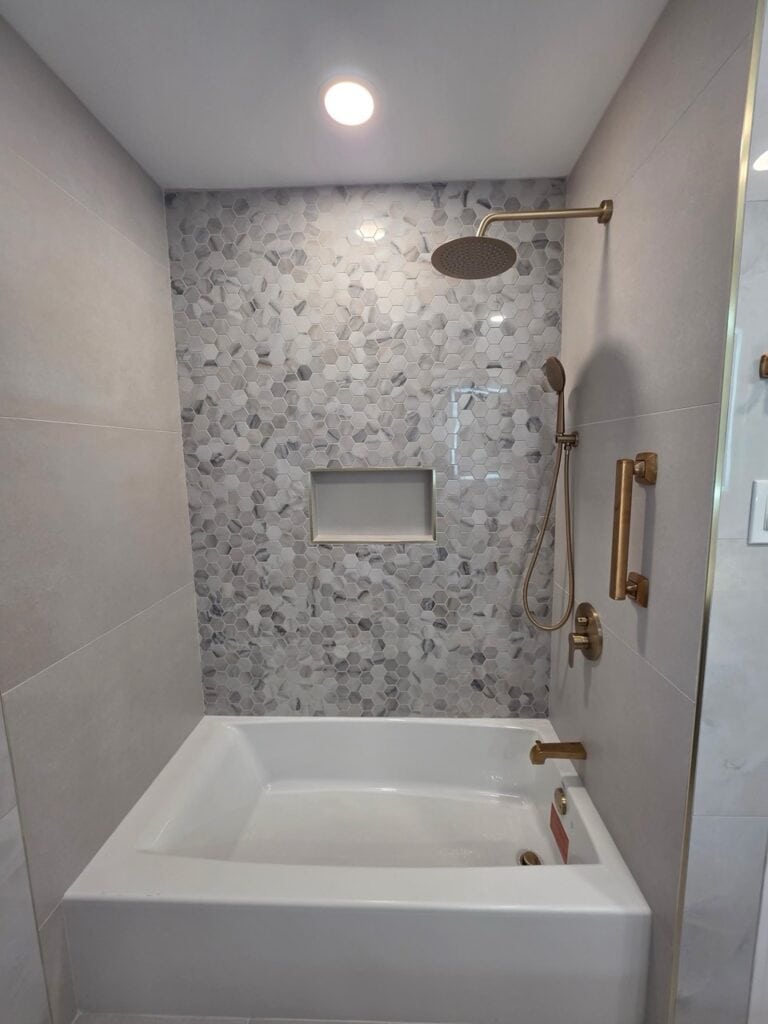 Contemporary bathroom shower with marble tiles and gold fixtures.