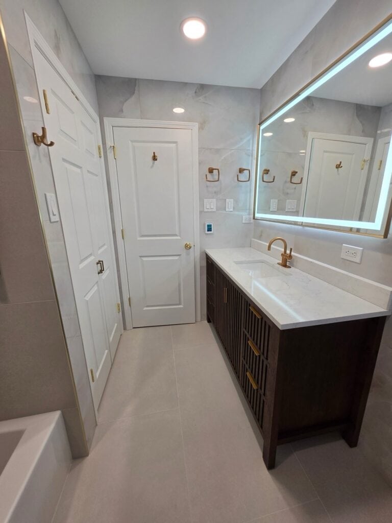 Elegant bathroom with large mirror, gold fixtures, and dark wood vanity.