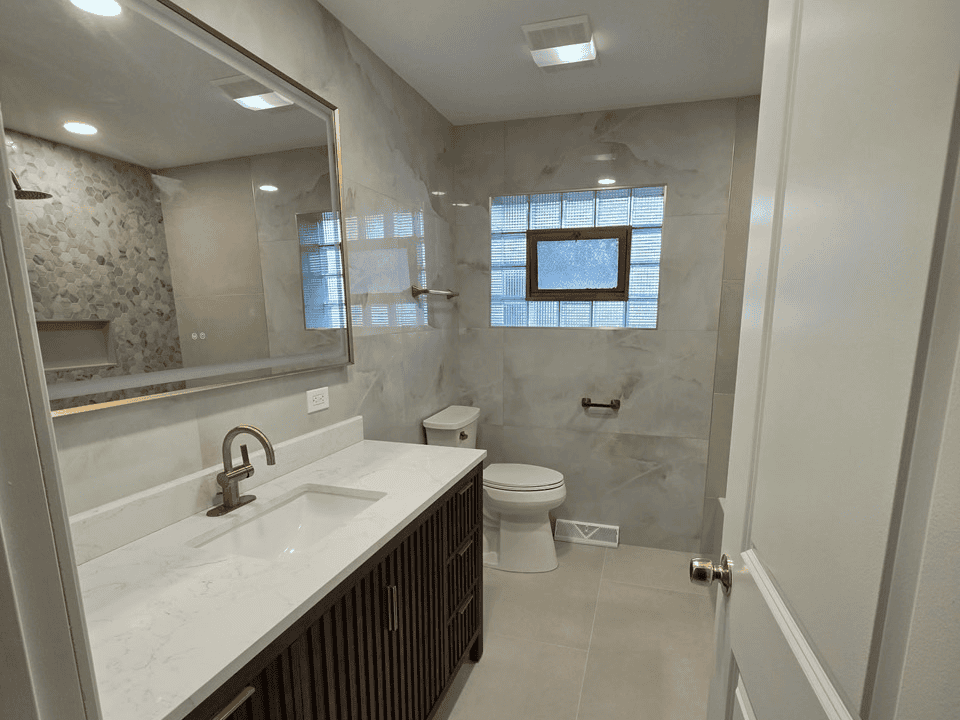 Contemporary bathroom with marble walls, vanity, and window for natural light.