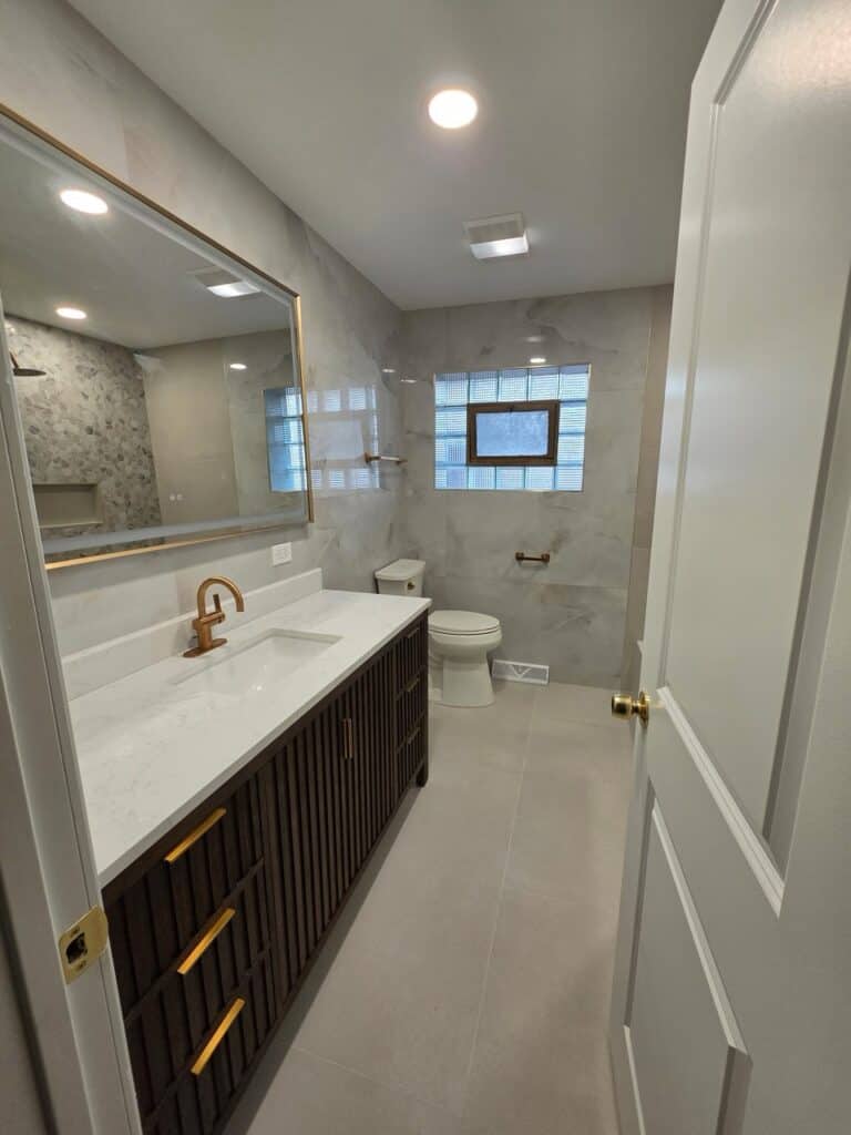 Contemporary bathroom with marble walls, wooden vanity, and modern fixtures.